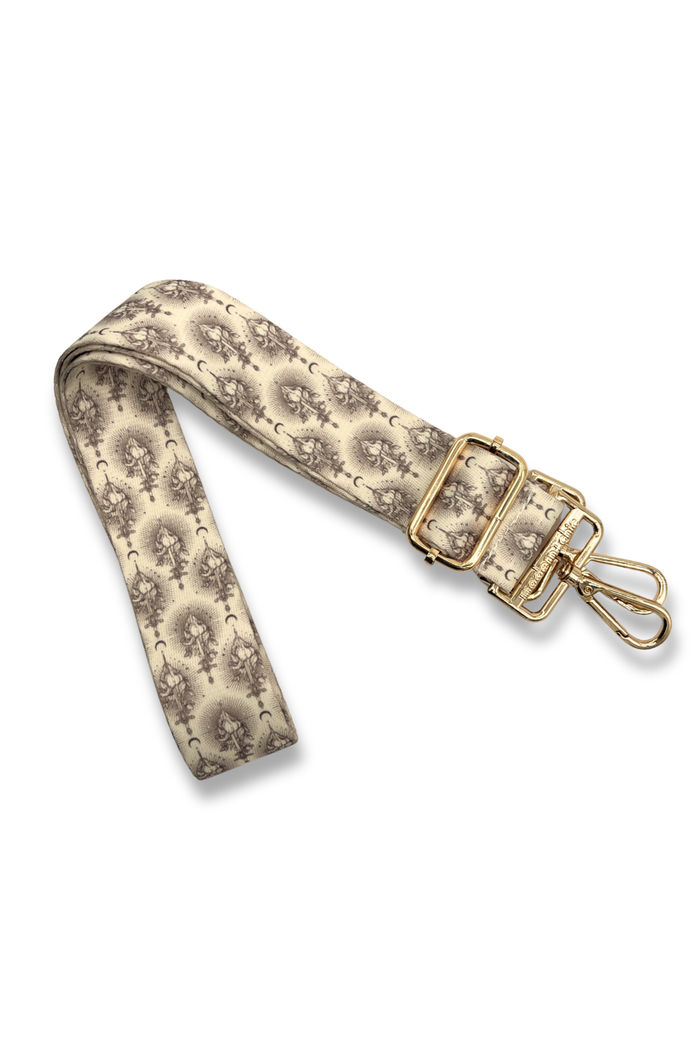 Sword-patterned strap with gold hardware on a white background