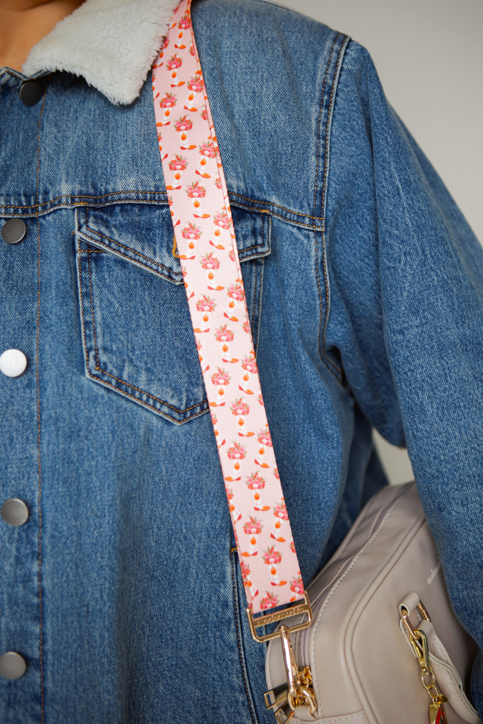 Pink cowboy boot and floral-patterned strap on a denim jacket and beige handbag