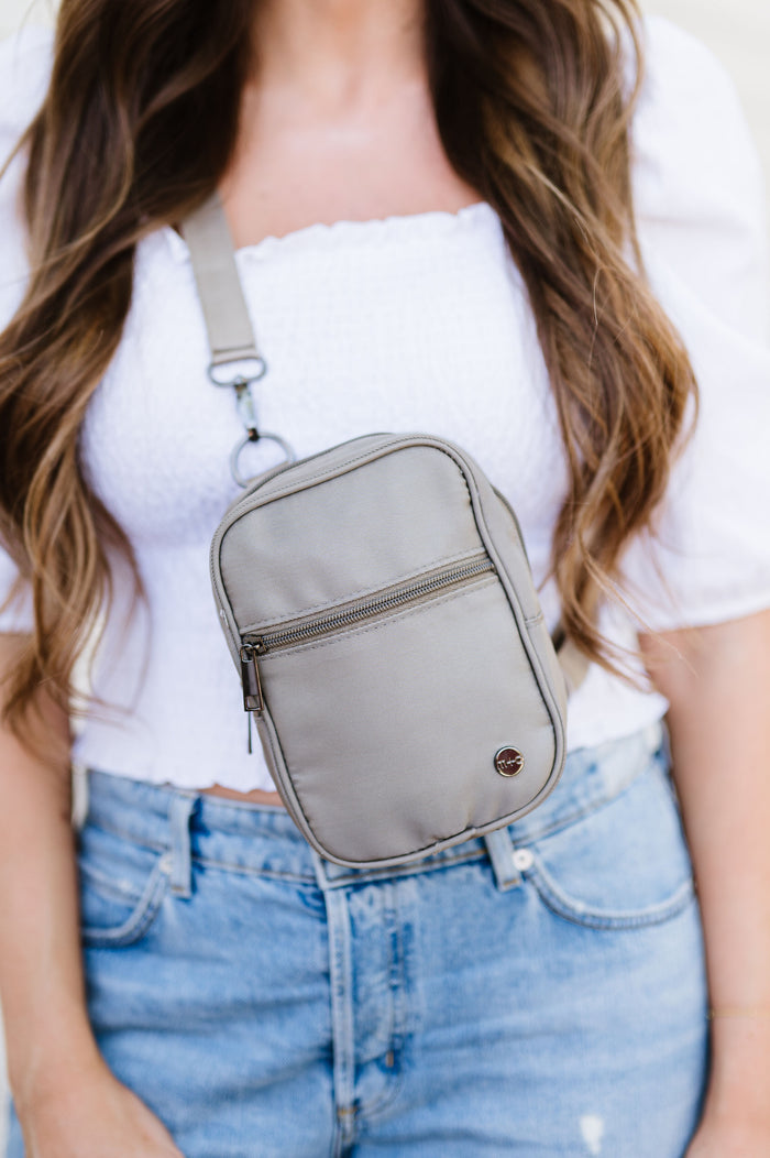 A woman wearing a grey Modern + Chic Lainey Convertible Crossbody Bag for Women with a white top and jeans.