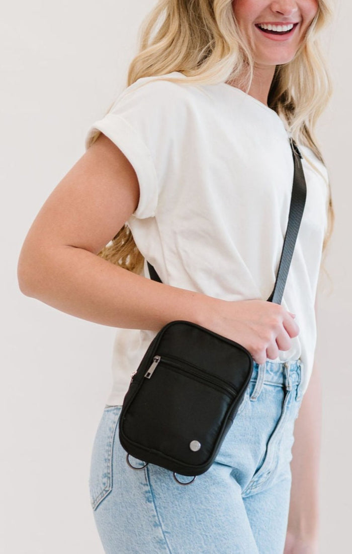 Woman wearing a black Modern + Chic Lainey Convertible Crossbody Bag for Women on a white top with jeans.