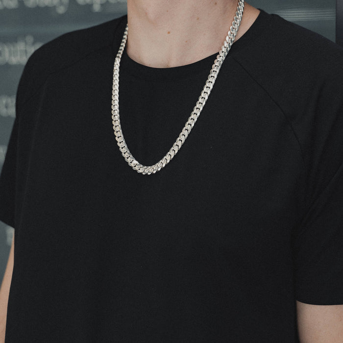 A silver Miami Cuban link chain necklace worn on a black t shirt