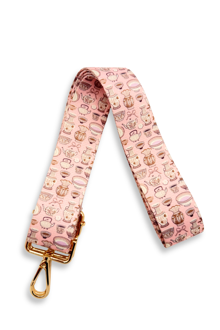 Pink strap with teapot-themed pattern and gold clasp on a white background