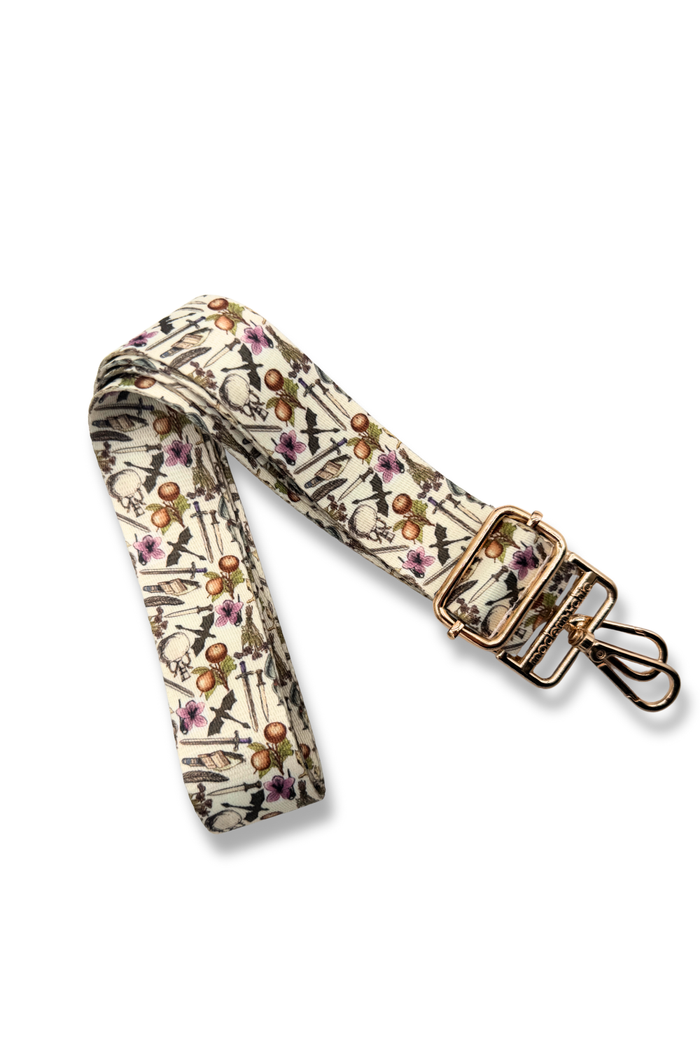 Floral patterned bag strap with gold hardware on a white background
